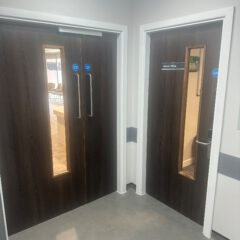 Two dark wooden doors are shown; one is a double door leading to a corridor, and the other is a single door labelled "Admin Office," both with vertical windows.